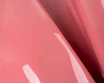 Peut inclure: Gros plan sur un tissu rose lisse et brillant avec un léger reflet. Le tissu est plié en deux, créant une ligne diagonale.