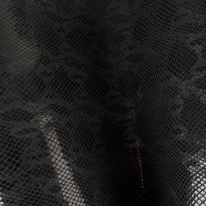 Peut inclure: Gros plan sur un tissu en peau de serpent noir avec un motif texturé en forme de diamant.