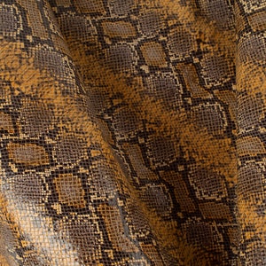 Puede incluir: Primer plano de una tela de piel de serpiente marrón y negra con un patrón texturizado.