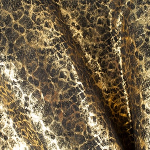 May include: Close-up of a textured fabric with a gold and black pattern. The fabric has a wrinkled, crinkled appearance.