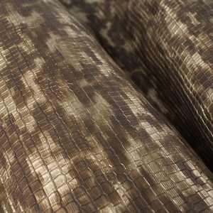 May include: Close-up of a brown and gold fabric with a textured, woven pattern.