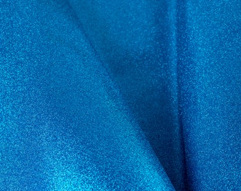 May include: Close-up of a blue fabric with a sparkly texture. The fabric is folded in a way that creates a soft, flowing look.