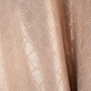 Puede incluir: Primer plano de una tela texturizada de color marrón claro con un sutil patrón de piel de serpiente. La tela está doblada y tiene un tacto suave y lujoso.