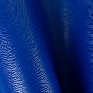 May include: A close-up of a blue textured leather material. The leather has a subtle sheen and a slightly wrinkled appearance.