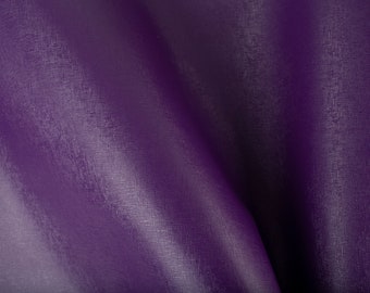 Pode incluir: Close-up de um tecido roxo escuro com um padrão texturizado sutil. O tecido é dobrado de forma a criar linhas suaves e fluidas.