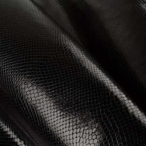 Puede incluir: Cuero de serpiente negro con un acabado texturizado y brillante.