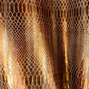 May include: Close-up of a gold and brown fabric with a snakeskin pattern.
