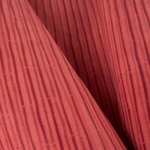 May include: Red fabric with a vertical striped pattern. The fabric has a textured surface and a subtle sheen.