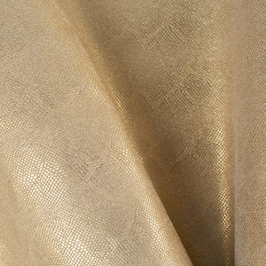 Op de afbeelding: Een close-up van een goudkleurige stof met een textuur die lijkt op een slang. De stof is dubbelgevouwen, waardoor een zacht, gedrapeerd effect ontstaat.