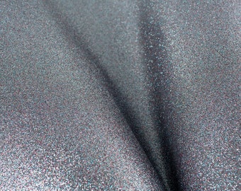 May include: Close-up of a silver fabric with a sparkly, glittery texture. The fabric is folded in a V-shape, creating a dramatic effect.