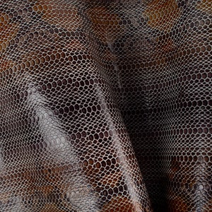 Puede incluir: Primer plano de tela de piel de serpiente marrón y gris con un patrón texturizado.