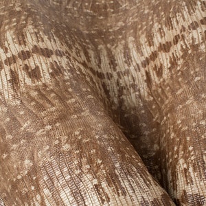 May include: Close-up of a brown and white textured fabric with a subtle pattern. The fabric has a soft, supple feel and a slightly iridescent sheen.