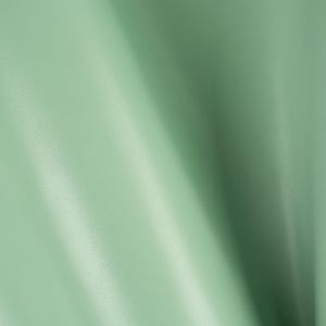 Könnte beinhalten: Nahaufnahme eines glatten, hellgrünen Stoffes mit einem dezenten Glanz. Der Stoff ist gefaltet und erzeugt einen weichen, fließenden Fall.