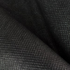 Peut inclure: Tissu noir avec un motif texturé en forme de grille. Le tissu est plié et a une surface douce et lisse.