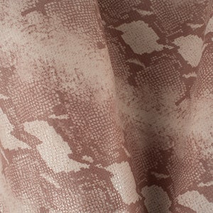 May include: Close-up of a pink and white snakeskin-patterned fabric with a textured surface.