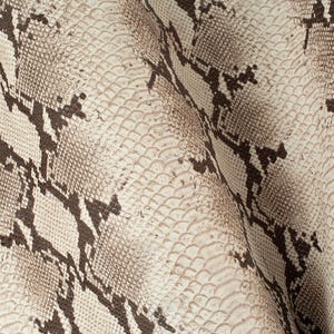 Könnte beinhalten: Nahaufnahme eines weißen und braunen Schlangenlederstoffs mit einem strukturierten Muster.