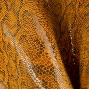 May include: Close-up of a textured fabric with a snakeskin pattern in shades of brown and gold.