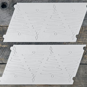May include: Two white plastic stencils with a repeating pattern of wavy lines. The stencils are designed for crafting and decorating.