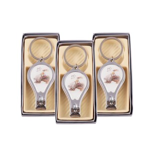 Peut inclure: Trois porte-cl&eacute;s argent&eacute;s avec coupe-ongles et un motif de b&eacute;b&eacute;. Chaque porte-cl&eacute;s a un fond blanc avec un b&eacute;b&eacute; en robe blanche et un motif floral. Les porte-cl&eacute;s sont dans des bo&icirc;tes individuelles avec un fond brun clair.