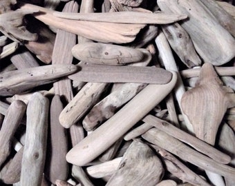 May include: A collection of weathered driftwood pieces in various shapes and sizes. The wood tones range from light beige to dark brown, with visible grain and textures. Some pieces are smooth, while others have knots and rough edges, creating a natural, rustic aesthetic.