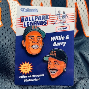 May include: Two baseball player enamel pins, Willie & Barry, with the numbers 24 and 25 on their caps. The pins are on a blue background with the text "Ballpark Legends" and "2 Pin Set Limited to 100".