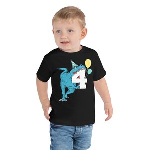 May include: A black t-shirt with a blue dinosaur wearing a party hat and holding a number 4. The dinosaur is holding balloons. The shirt is for a child.