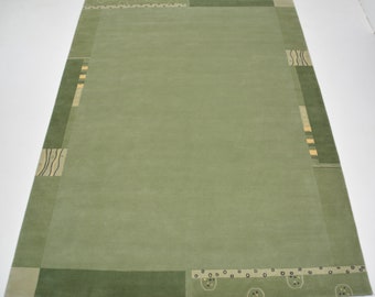 Op de afbeelding: Een groen vloerkleed met een geometrisch patroon in tinten groen, beige en zwart. Het vloerkleed heeft een modern ontwerp en is gemaakt van wol.