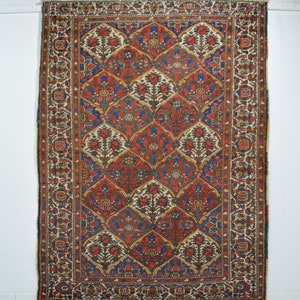 May include: A vintage Persian rug with a red, blue, and cream color scheme. The rug features a repeating pattern of stylized floral motifs and geometric shapes.
