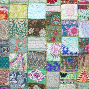 May include: A colourful patchwork quilt featuring a range of floral and geometric designs. The quilt is made from various fabrics and textures, and is stitched together in a grid pattern.