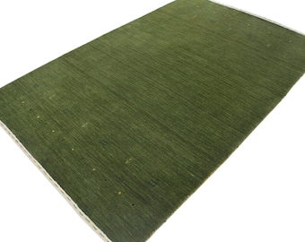 Op de afbeelding: Een groen vloerkleed met een subtiel patroon van kleine gele stippen. Het kleed heeft een witte rand.