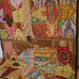 Può includere: Un arazzo da parete colorato in patchwork con ricami intricati e dettagli perlati. L'arazzo presenta una varietà di tessuti e trame, tra cui velluto, seta e cotone. L'arazzo è un'opera d'arte vibrante ed eclettica che aggiungerebbe un tocco di stile bohémien a qualsiasi stanza.
