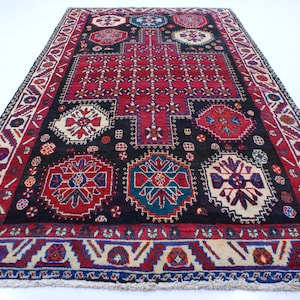 May include: A traditional Turkish rug with a red, black, and blue geometric pattern. The rug has a central medallion and a border with intricate designs.