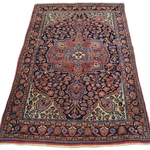 May include: A traditional Persian rug with a navy blue background and a central medallion in shades of red, cream, and blue. The rug has a floral pattern and a border with intricate details.