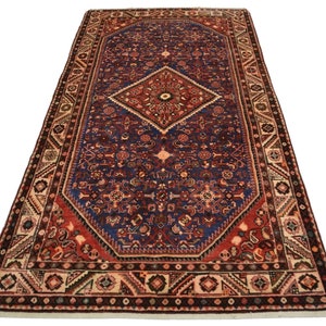 May include: A traditional Persian rug with a deep blue background and intricate red, cream, and brown patterns. The rug features a central diamond shape with a floral design and a border with geometric motifs.