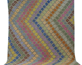 May include: A colorful rug with a geometric diamond pattern in shades of blue, green, yellow, orange, pink, and brown. The rug has a fringe border.