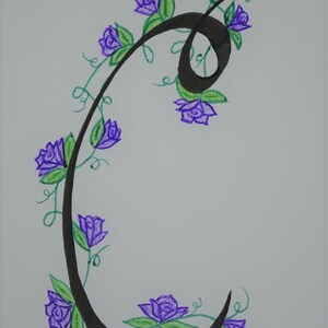May include: A black calligraphic letter C with a vine of purple flowers and green leaves winding around it.