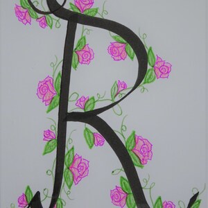 May include: A black calligraphic letter R with pink roses and green leaves drawn around it.