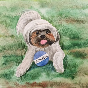 May include: A watercolor painting of a small, white dog with brown fur around its eyes and a pink tongue sticking out. The dog is holding a blue ball with the word "Winston" written on it. The dog is sitting in a field of green grass.