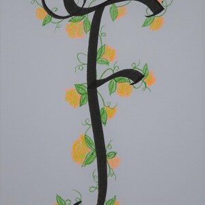 May include: A black calligraphic letter F with a vine of green leaves and orange flowers winding around it.