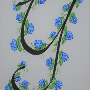 May include: A black calligraphic letter 'J' with blue roses and green leaves winding around it.