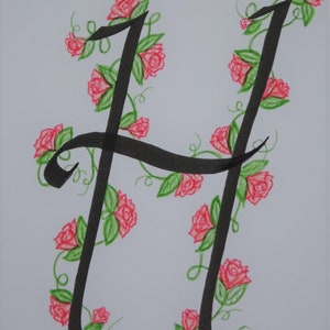 May include: A black calligraphy letter H with a vine of pink roses and green leaves around it.