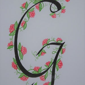 May include: A black calligraphic letter G with a vine of red roses and green leaves winding around it.