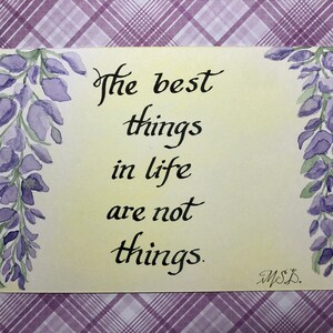 May include: A watercolor painting with a yellow background and purple wisteria flowers on either side. The text "The best things in life are not things." is written in black calligraphy.