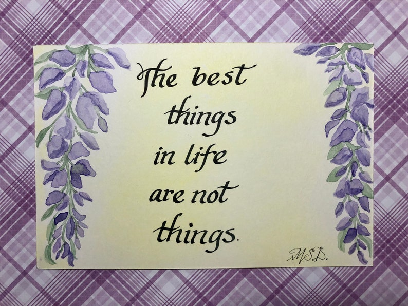 May include: A watercolor painting with a yellow background and purple wisteria flowers on either side. The text "The best things in life are not things." is written in black calligraphy.
