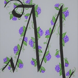 May include: A hand-drawn letter M with a black ink outline. The letter is decorated with purple flowers and green vines.