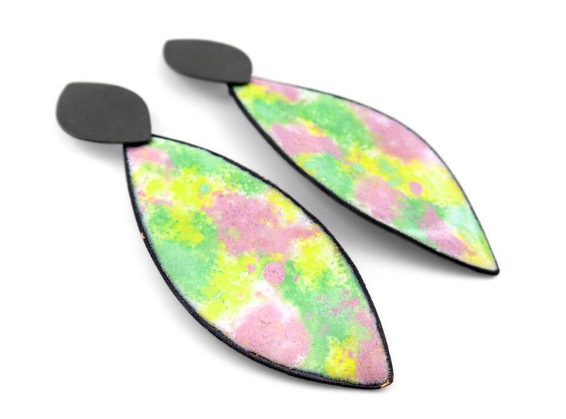 May include: A pair of dangle earrings with a black metal base and a green, pink, and yellow abstract design.