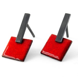 May include: A pair of red enamel earrings with black metal accents. The earrings are square shaped and have a simple, geometric design.