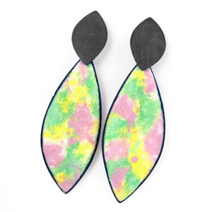 May include: A pair of dangle earrings with a black metal top and a colorful, abstract design. The design features shades of pink, green, and yellow.