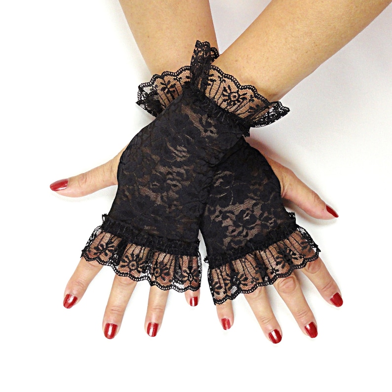 Puede incluir: Un par de guantes sin dedos de encaje negro con bordes con volantes. Los guantes est&aacute;n hechos de encaje delicado y transparente y tienen un patr&oacute;n floral.