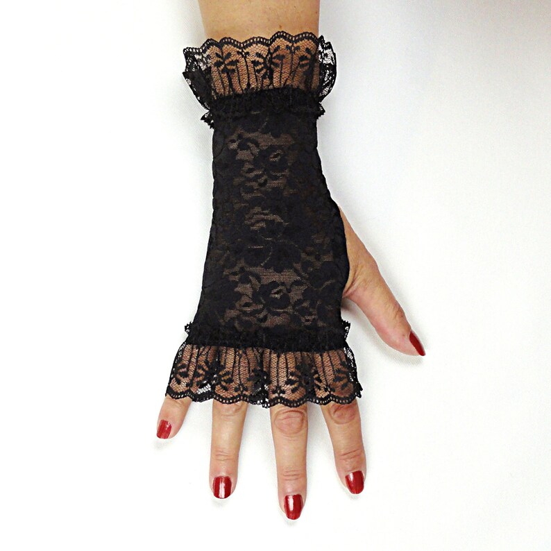 Puede incluir: Guantes sin dedos de encaje negro con un borde de volantes. Los guantes est&aacute;n hechos de una tela delicada y transparente y tienen un patr&oacute;n floral.